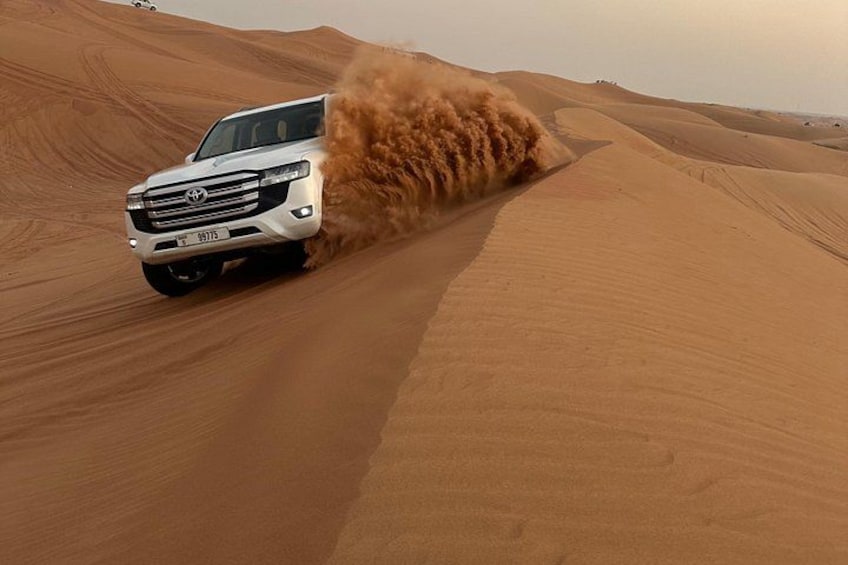 Un SUV blanco circulando por un desierto, levantando arena con sus neumáticos. 1