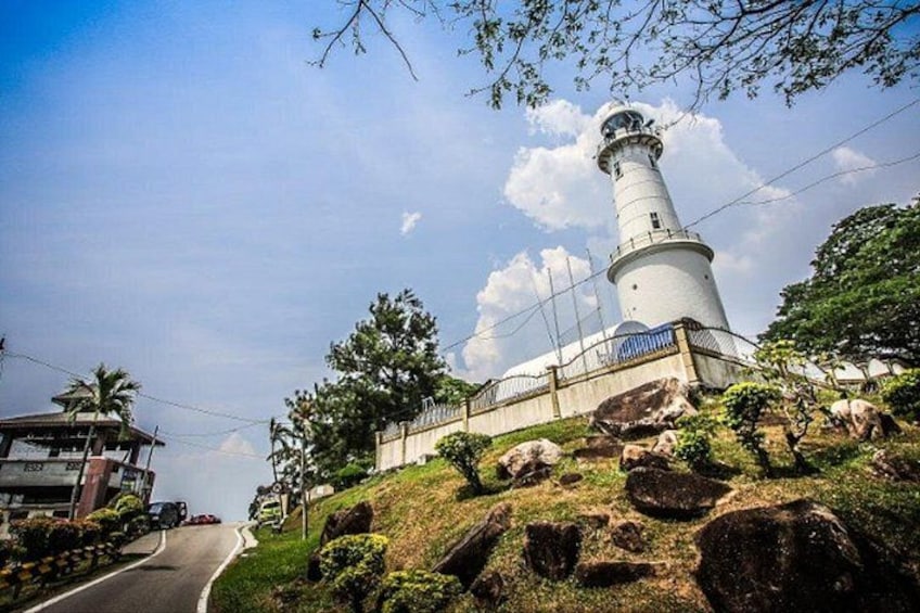 A lighthouse on a hill with a road in the foreground. 2