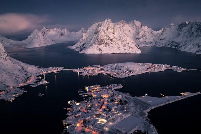 Ein verschneiter Fjord mit einer Stadt am Fuße, umgeben von Bergen. 1