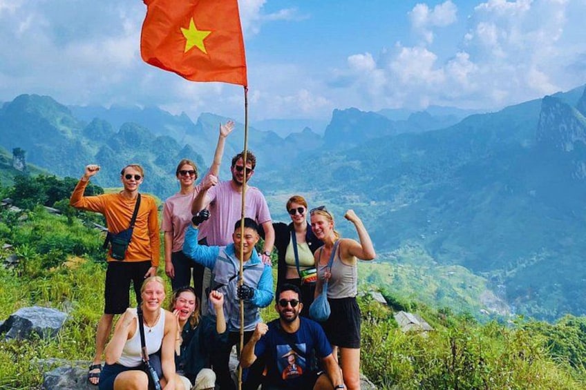 Eine Gruppe von Menschen posiert mit einer Flagge auf einem Berggipfel. 2