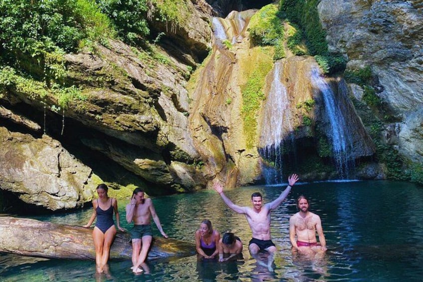 Eine Gruppe von Menschen in einer natürlichen Wasserlandschaft mit Wasserfall und Felsklippen. 1