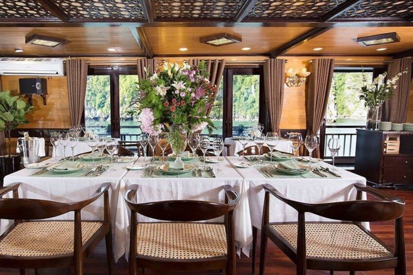 A restaurant with a long dining table set for a meal, surrounded by chairs. 4
