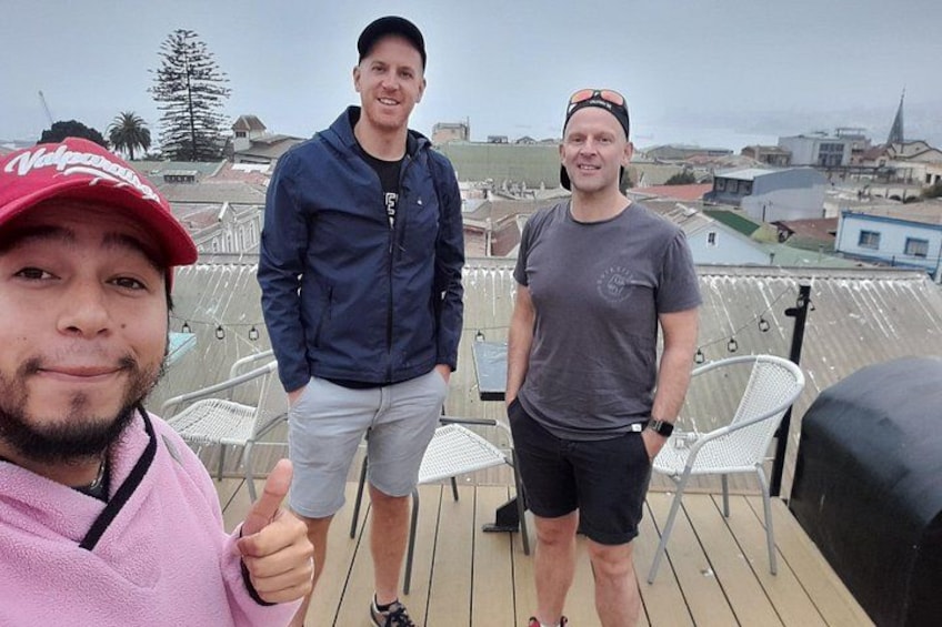 Three people on a rooftop with a cityscape in the background. 5