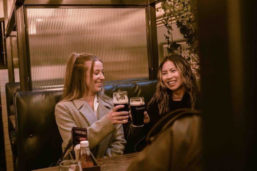 Two people sitting at a table with a bottle of beer and a glass. 5