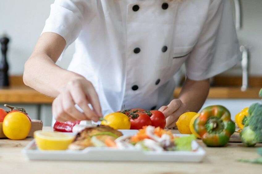A chef preparing food with vegetables and a plate of food on a table. 3