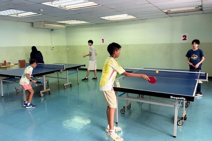 A table tennis court with players practicing. 2