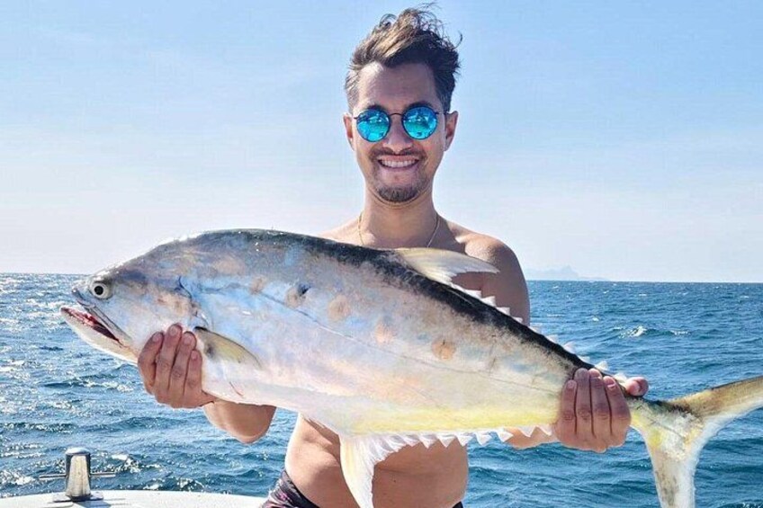 A person holding a large fish on a boat with the ocean in the background. 5