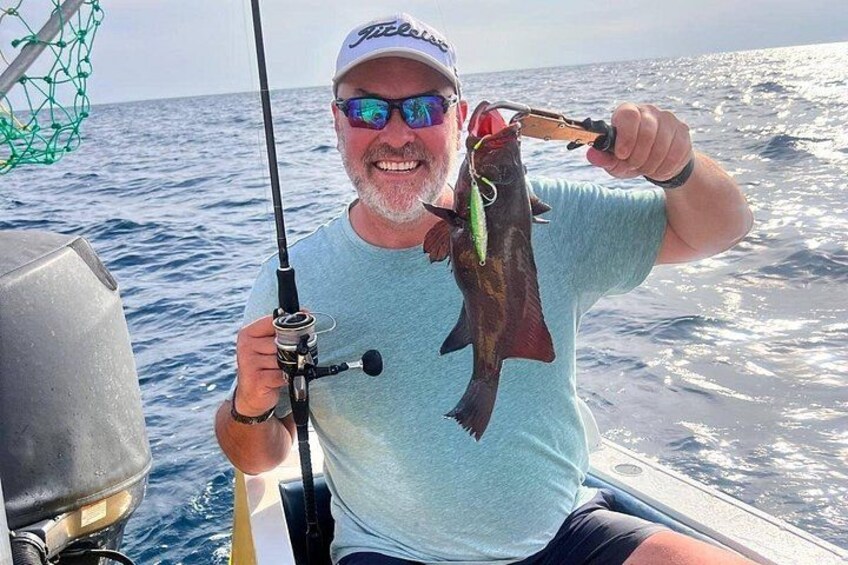 A person holding a fish on a boat with the ocean in the background. 4