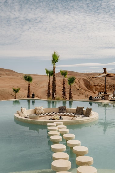 A pool with lounge chairs and palm trees in a desert landscape. 2