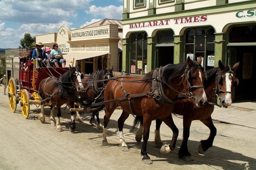 A horse-drawn carriage on a street with buildings in the background. 1
