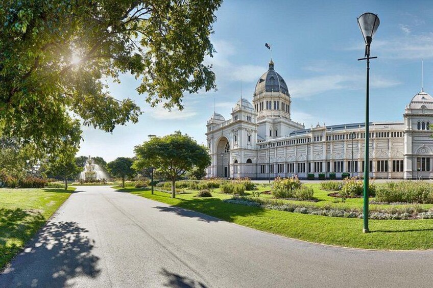 A grand building with domes, a well-maintained garden, and a clear sky. 2