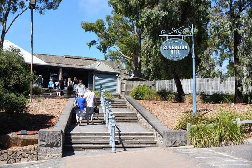 A sign reading 'Welcome to Sovereign Hill' with people walking up a set of stairs. 4
