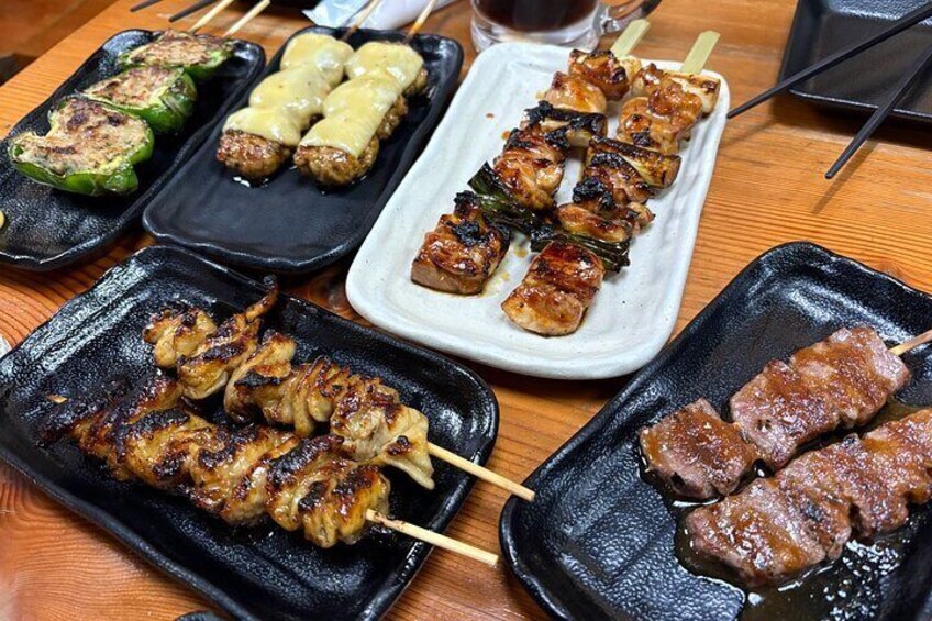 Assortiment de brochettes grillées et de plats servis dans des assiettes noires. 5