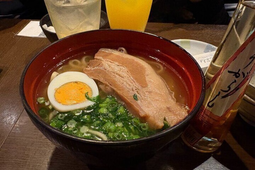 Un bol de ramen garni d’un œuf mollet, de porc et de légumes verts. 2