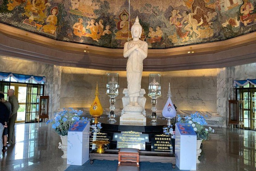 A temple interior with a central statue, incense burners, and floral arrangements. 3