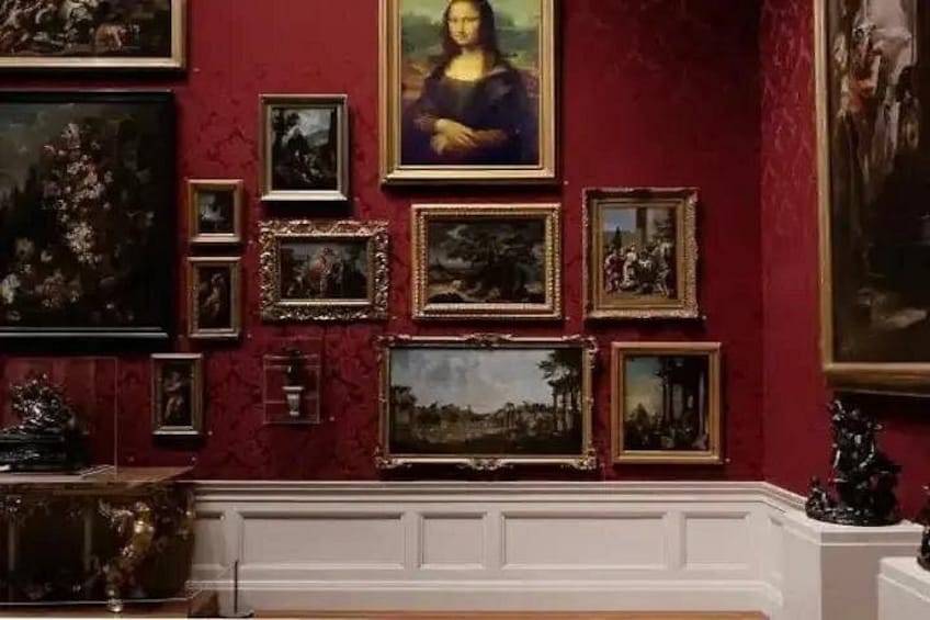 Una galería con varias pinturas enmarcadas sobre un muro rojo. 2