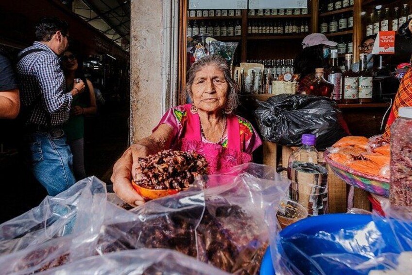 Una persona sostiene un plato de comida en un puesto de mercado, con diversos productos envasados al fondo. 3