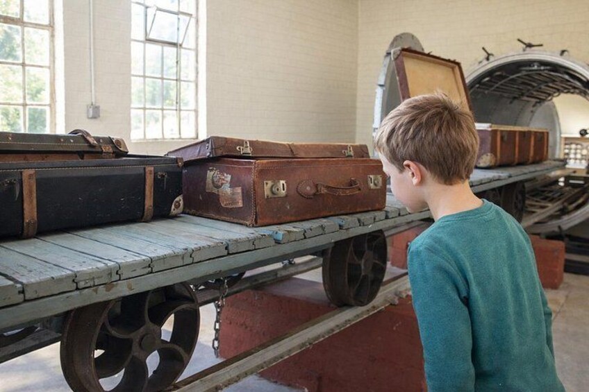 Un bambino osserva delle valigie d'epoca su un carrello in un museo. 2