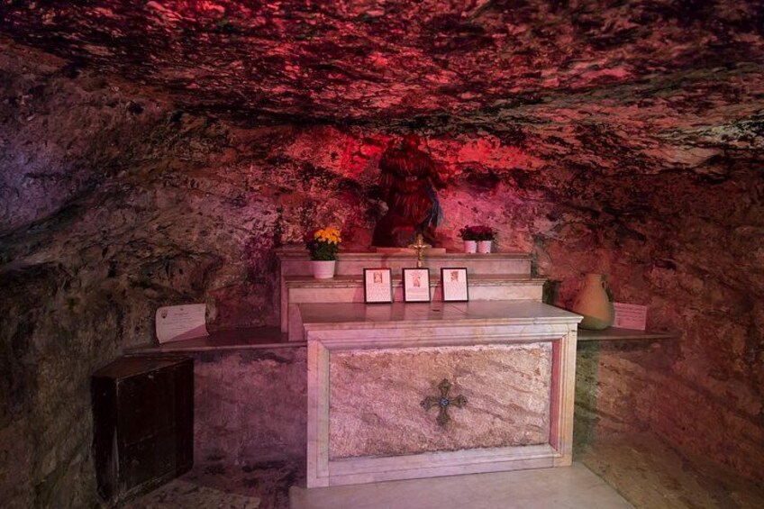 L’intérieur d’une grotte abritant un autel en marbre, des icônes religieuses et une statue. 2