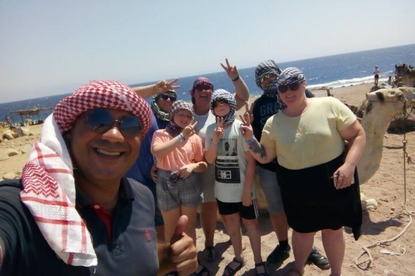 En gruppe mennesker på en strand med en kamel i baggrunden. 3