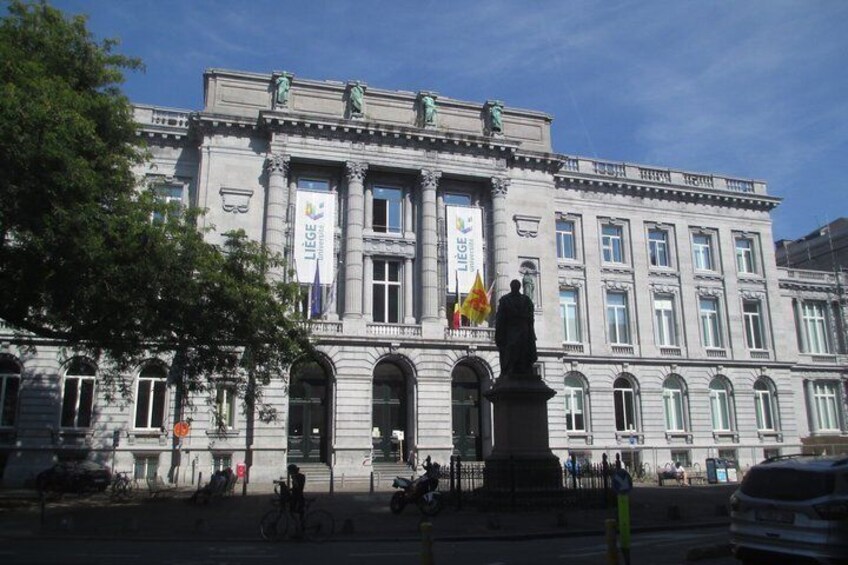 A large, historic building with columns and a statue in front. 2