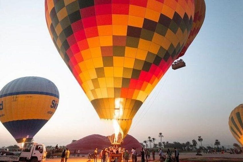 Hot air balloons with passengers, a vehicle, and a crowd of people. 1