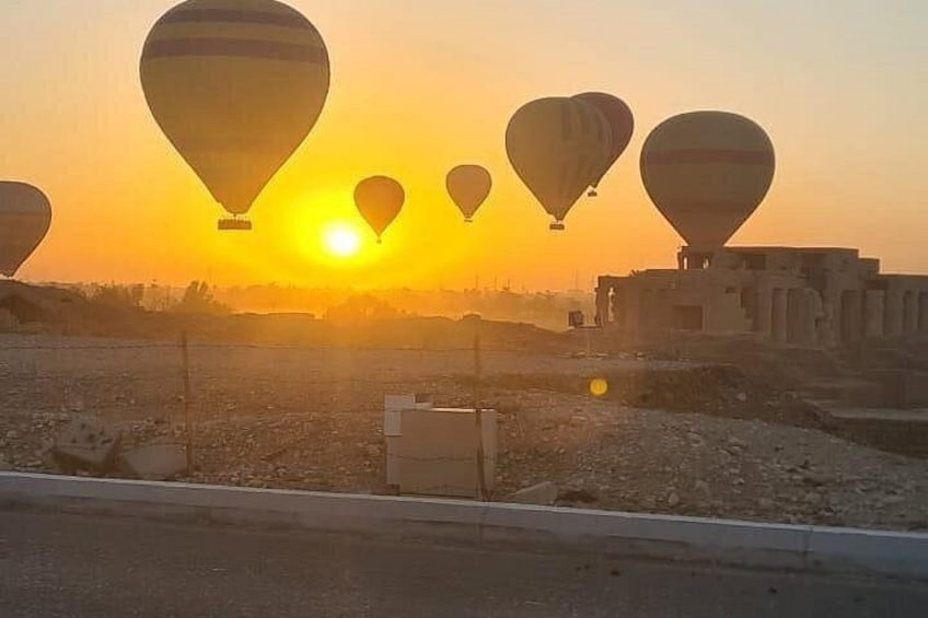 Hot air balloons, a sunset, and a desert landscape with buildings. 3