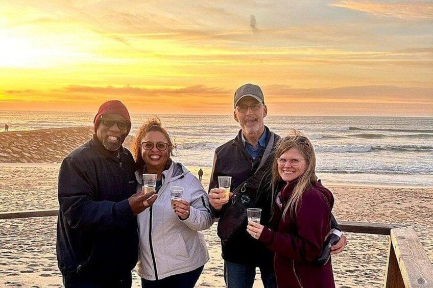 A group of people on a wooden boardwalk by the ocean during sunset. 3