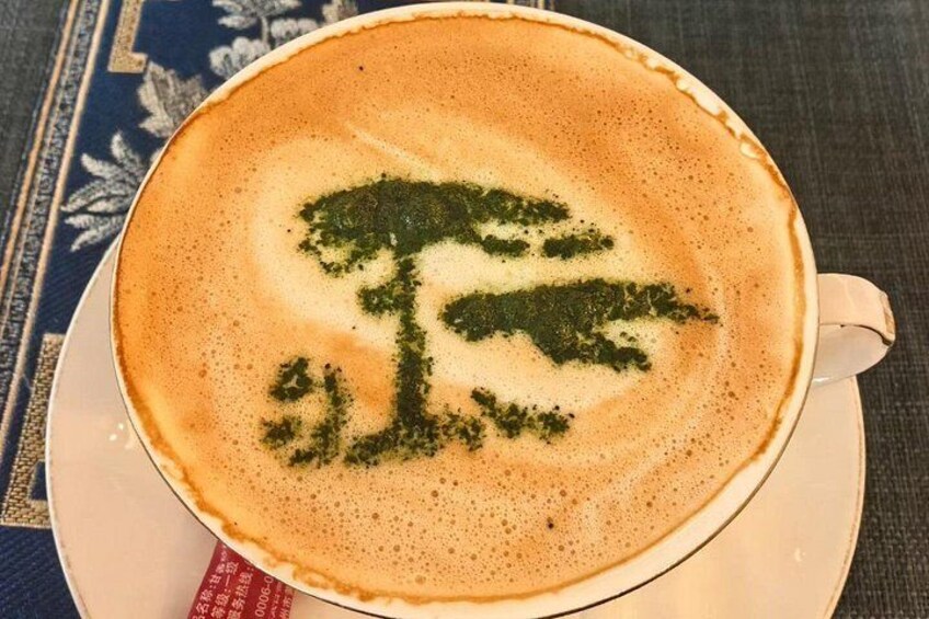 A cup of coffee with a latte art tree design on a saucer. 2