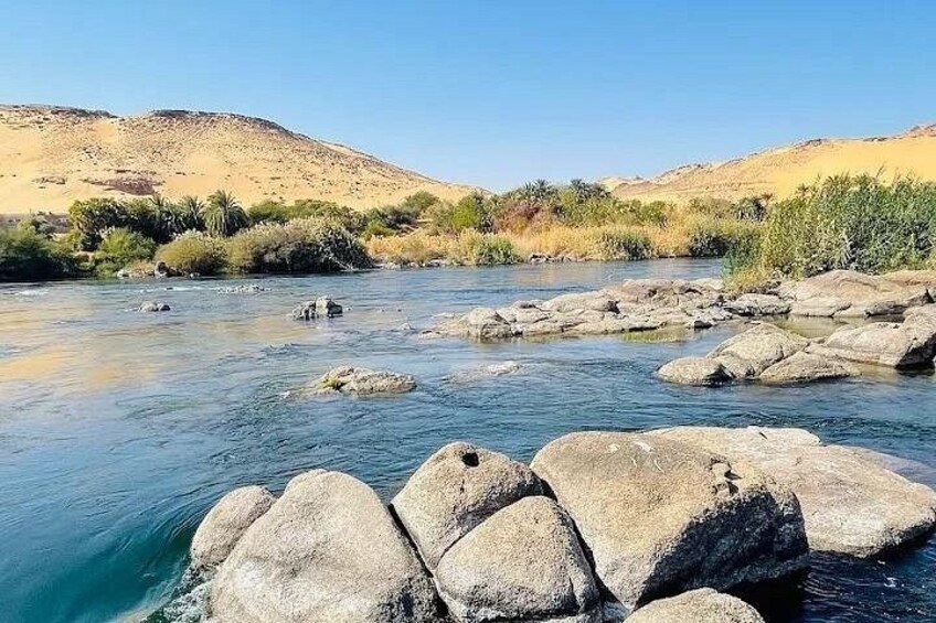 Une rivière dont le lit est parsemé de gros rochers, entourée de collines et d’une végétation clairsemée. 1