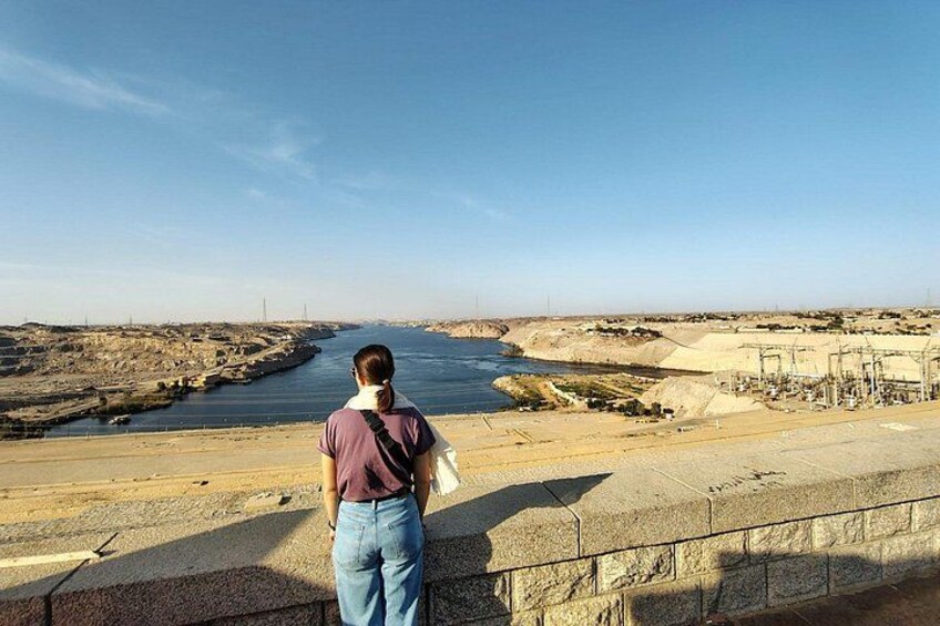 Une personne se tient debout sur une corniche en béton, surplombant une rivière, avec des infrastructures industrielles en arrière-plan. 4