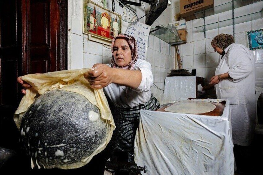 Una mujer manipula una masa grande en una cocina. 3