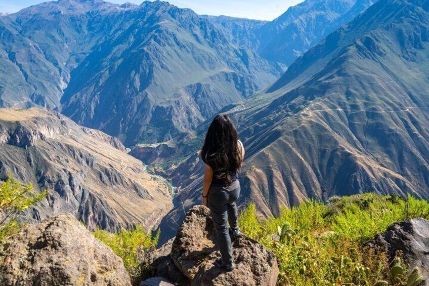 A person standing on a rocky outcrop overlooking a mountainous landscape. 2