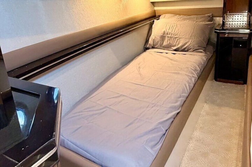 Un petit lit bien fait, avec un matelas blanc et une literie beige, dans une chambre de taille modeste. 1