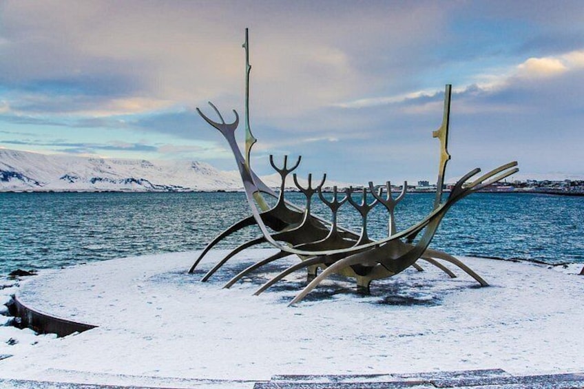 En metalskulptur der forestiller et vikingeskib med et snelandskab og bjerge i baggrunden. 2