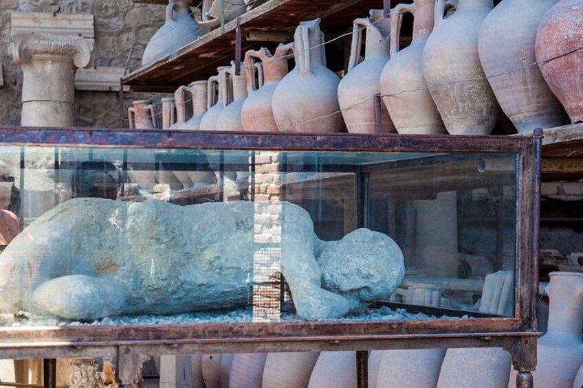 A glass display case with ancient pottery and a stone sculpture. 4