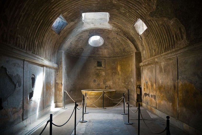 An arched room with a central altar, stone walls, and a barred area. 3