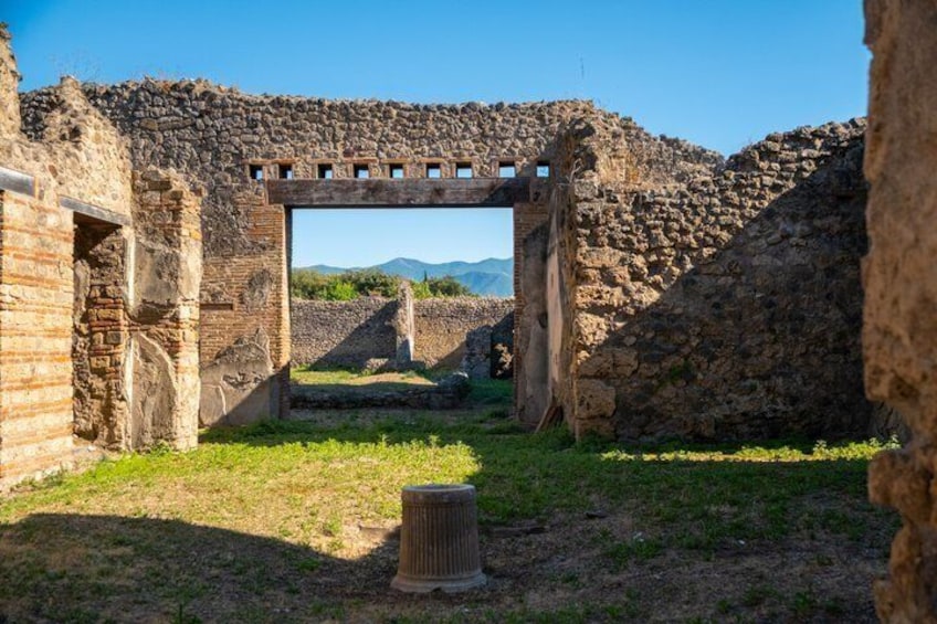 Ancient ruins with stone walls and an archway leading to a distant view of mountains. 4