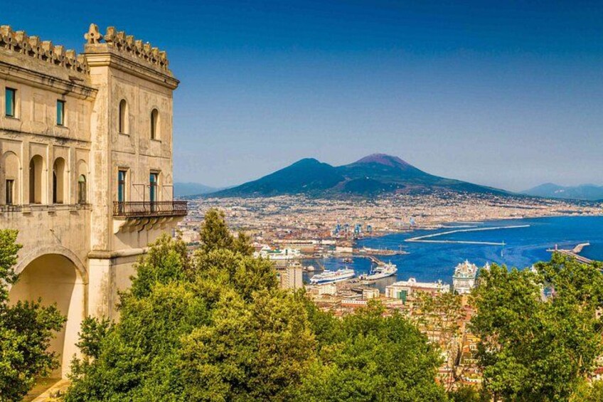 A coastal cityscape with a prominent historical building, a volcano in the background, and a harbor with boats. 4