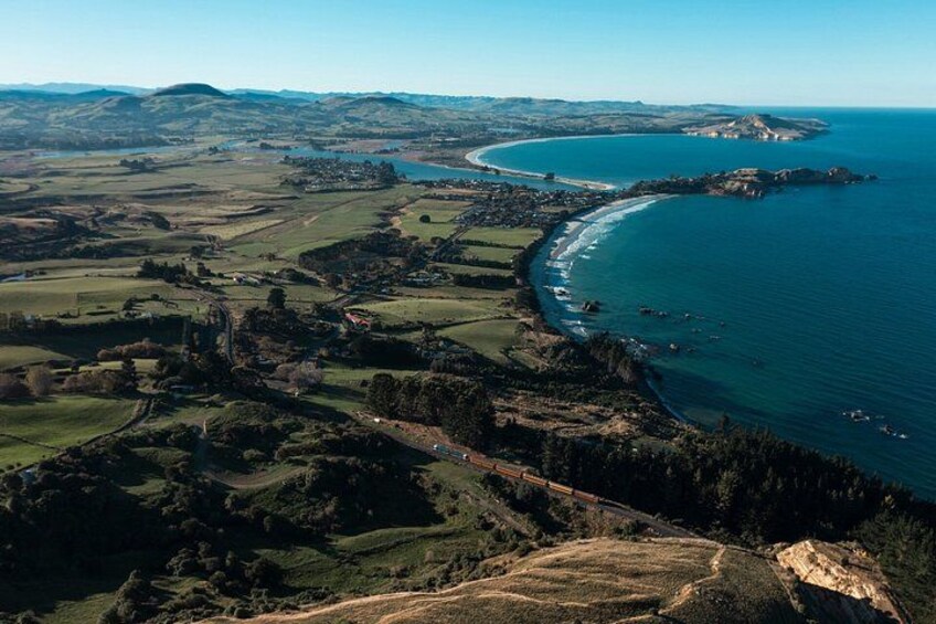 A coastal landscape with rolling hills, a winding road, and a beach. 2