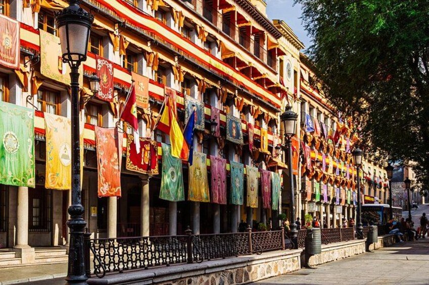 A street lined with colorful flags, historic buildings, and a decorative fence. 2