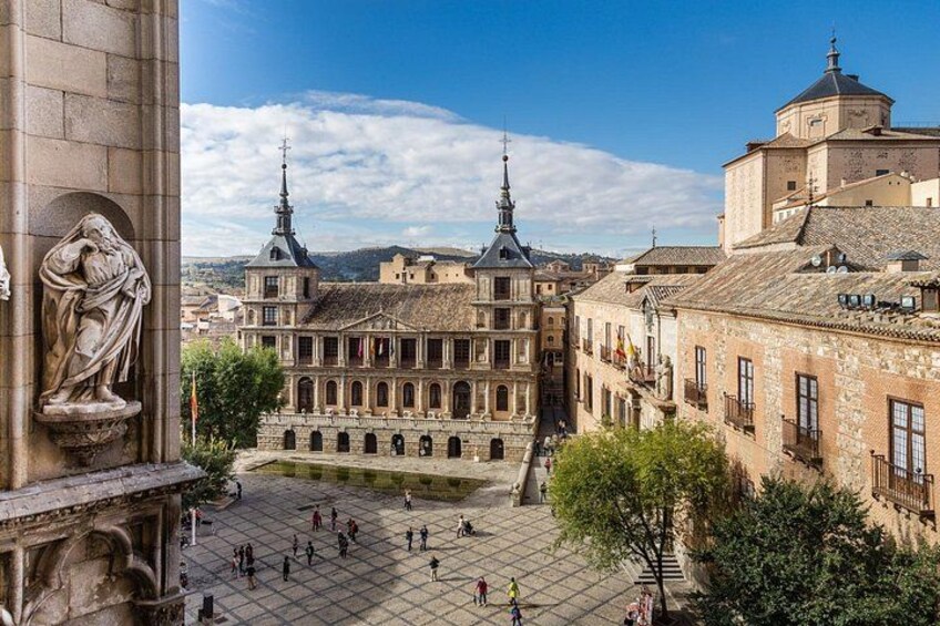 A historic plaza with a large building featuring two spires, surrounded by traditional architecture. 3