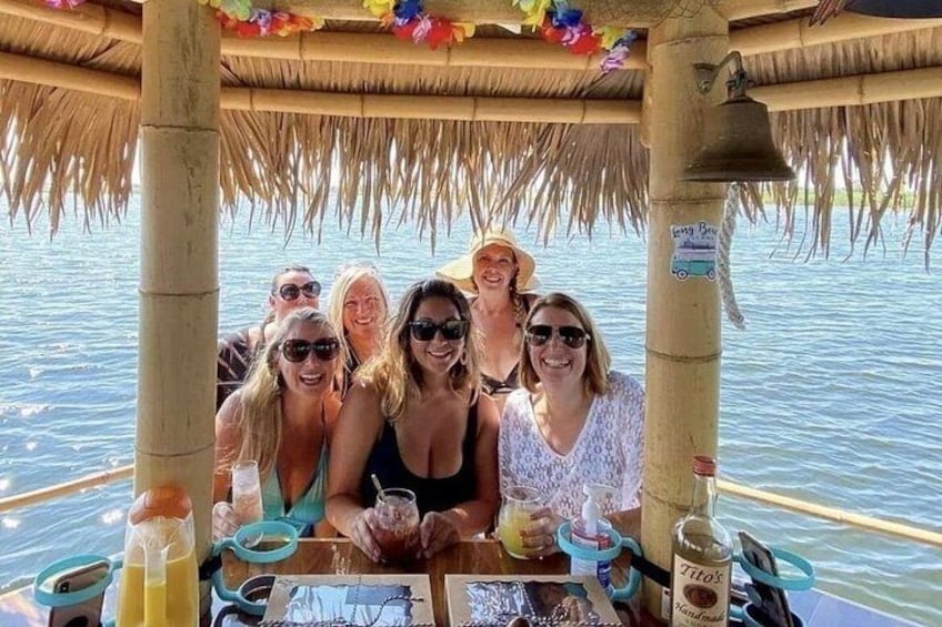 A group of people on a boat with a thatched roof, surrounded by water. 2