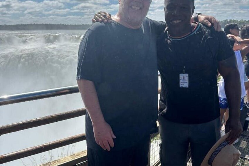 Two people standing by a waterfall with a railing. 1