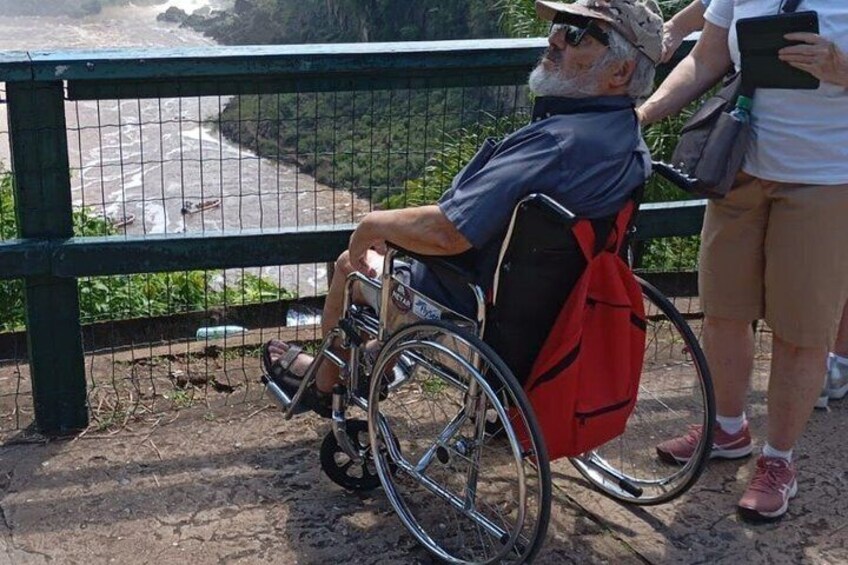 A person in a wheelchair by a railing overlooking a beach. 5
