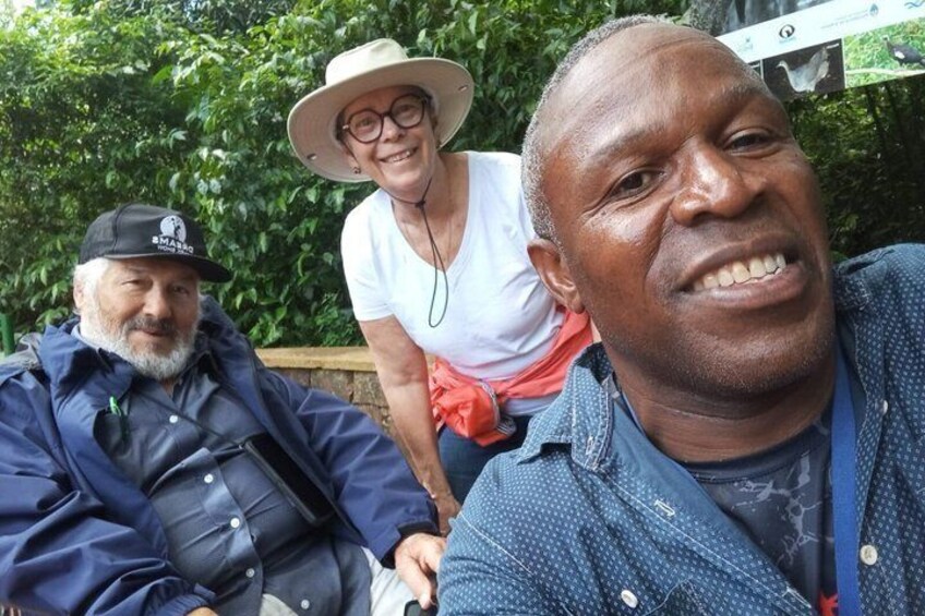 Three people outdoors, one wearing a hat and a jacket, another in a blue shirt, and a third in a white shirt. 3