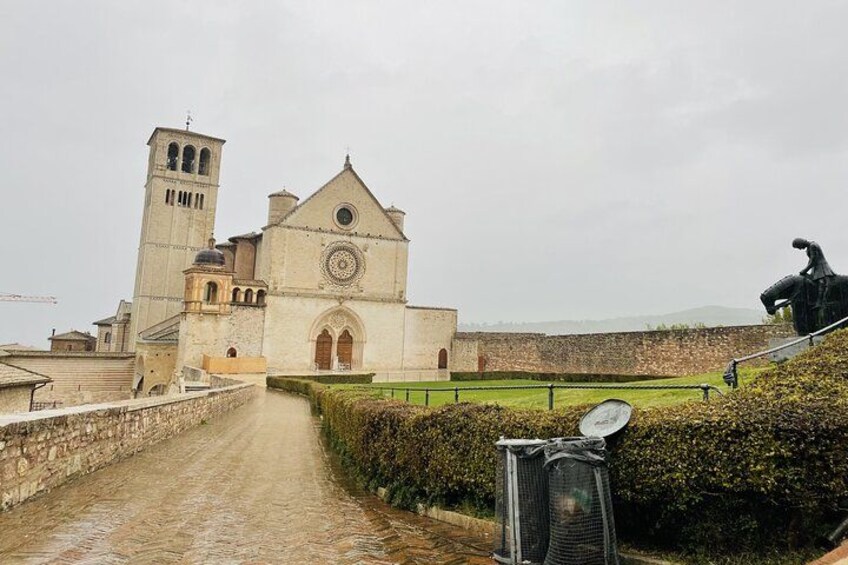 A historic church with a bell tower, a statue, and a pathway leading to it. 3