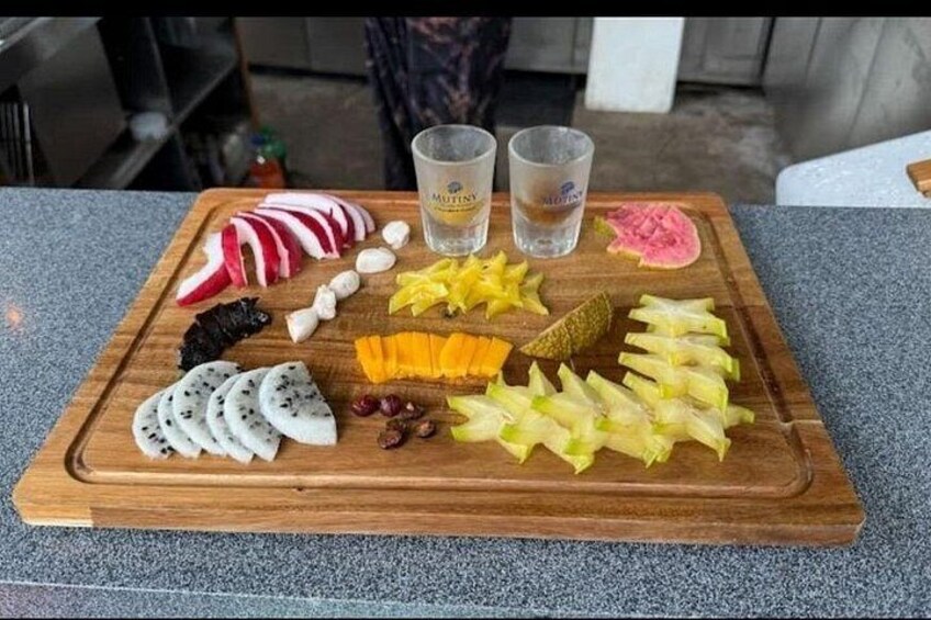 A wooden cutting board with various fruits and vegetables, including sliced radishes, grapes, and a cucumber. 4
