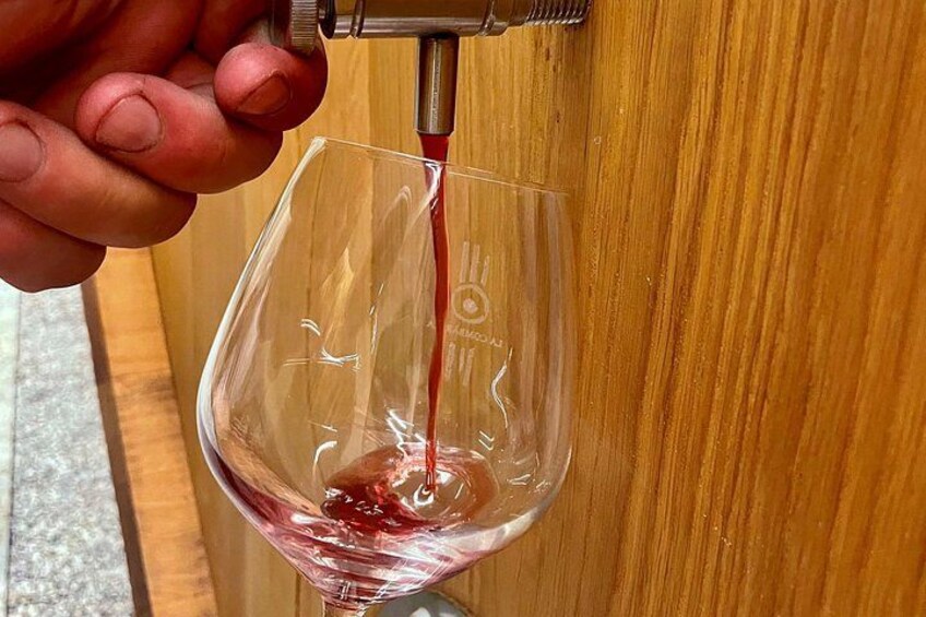 A hand pouring red liquid into a clear glass. 2