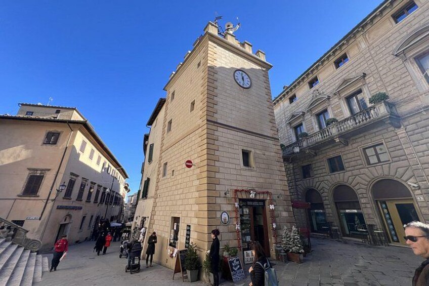 A historic square with a clock tower, cobblestone streets, and traditional buildings. 4